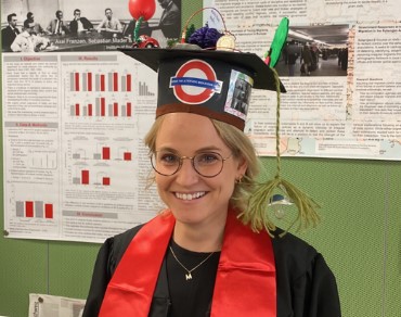 A photo of Annika Wyss wearing a doctoral hat; the hat depicts important aspects of her dissertation, e.g., a brain, tDCS electrodes, and green trees.